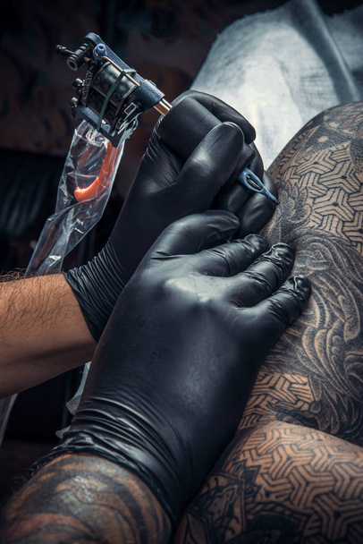 Maestro del tatuaje trabajando tatuajes en salón de tatuajes
 - Foto, Imagen