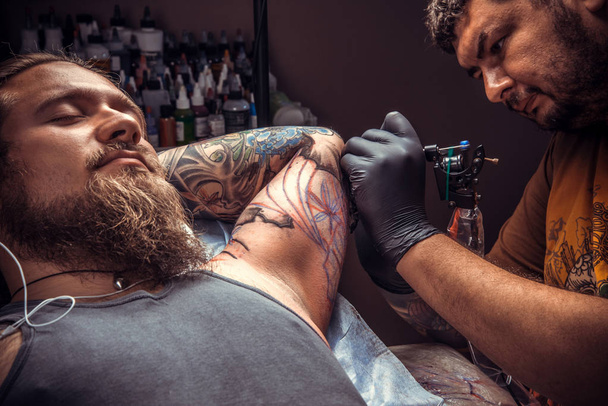 Tetováló mester működő tetoválás tattoo studio. / szakmai tattooist tesz tattoo tetováló szalon. - Fotó, kép