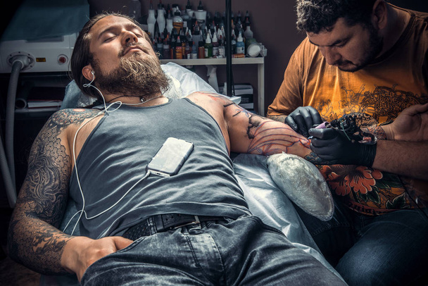 Майстер робить татуювання в студії татуювання / Професійний татуювання робить татуювання в татуювальному салоні
. - Фото, зображення