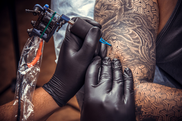 Professional tattooer works in tattoo parlor - Photo, Image
