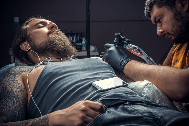 Tattooer making a tattoo in tatoo salon. / Professional tattooist makes cool tattoo in tattoo studio
. - Фото, изображение