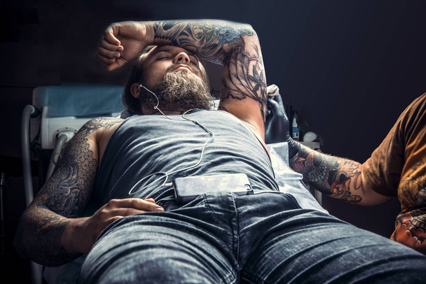 Tatuaje profesional hace tatuaje en salón de tatuaje
 - Foto, Imagen