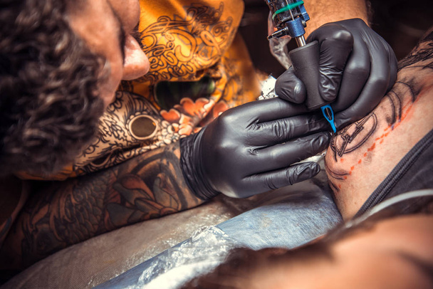 Профессиональный татуировщик делает татуировку в тату-салоне
 - Фото, изображение