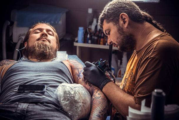 Artista profesional del tatuaje haciendo un tatuaje en el salón de tatuajes
 - Foto, Imagen