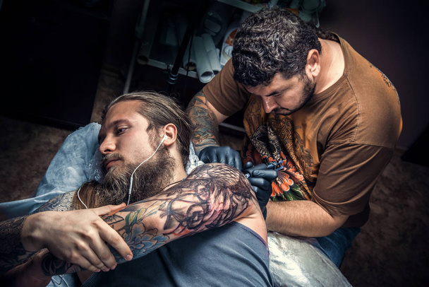 Professional tattooer working tattooing in tattoo parlor - Photo, Image