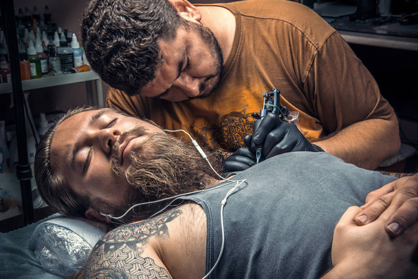 Especialista en tatuajes que muestra el proceso de hacer un tatuaje en el salón de tatuajes
 - Foto, Imagen