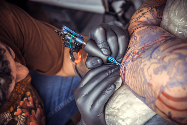 Tatuaje trabajando tatuajes en estudio. / Tatuaje profesional en el trabajo en el salón
. - Foto, Imagen