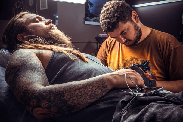 Professzionális tetováló művész csinál tetoválás tattoo studio. / szakmai tattooist pózol tetováló Studió. - Fotó, kép