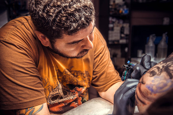 Professionele tattooer maakt tattoo in tattoo salon - Foto, afbeelding
