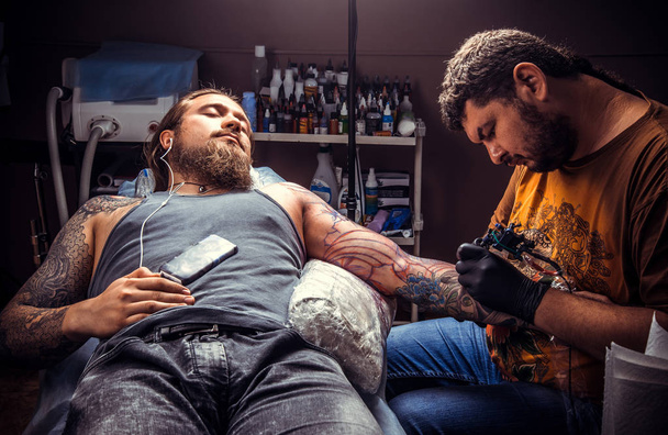 Tatuaje de trabajo tatuador en salón de tatuajes. / Artista profesional del tatuaje en el trabajo en el estudio de tatuajes
. - Foto, imagen