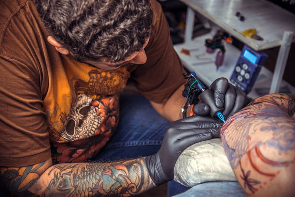 Майстер татуювання показує процес створення татуювання в татуювальному салоні
 - Фото, зображення