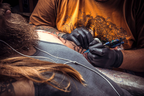 Tatuointi asiantuntija poseeraa tatuointi salissa. / Ammattimainen tatuoija töissä salonki
. - Valokuva, kuva
