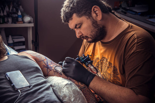Tatuaje profesional posando en un estudio de tatuajes. / Master trabaja en un salón de tatuajes
. - Foto, imagen