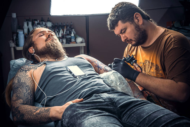 Tattooist pracy tatuażu w salonie. / Professional tattoo artysty w pracy w studio tatuażu. - Zdjęcie, obraz