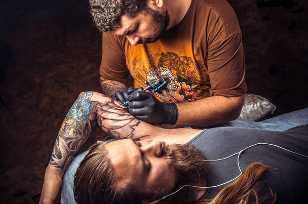 Professional tattooist posing in studio./Professional tattooer makes tattoo pictures in tattoo studio. - Foto, Imagem