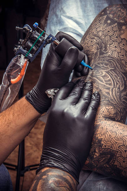 Tattoo specialist making a tattoo in tattoo studio./Professional tattooist makes tattoo in tattoo parlor. - Photo, Image