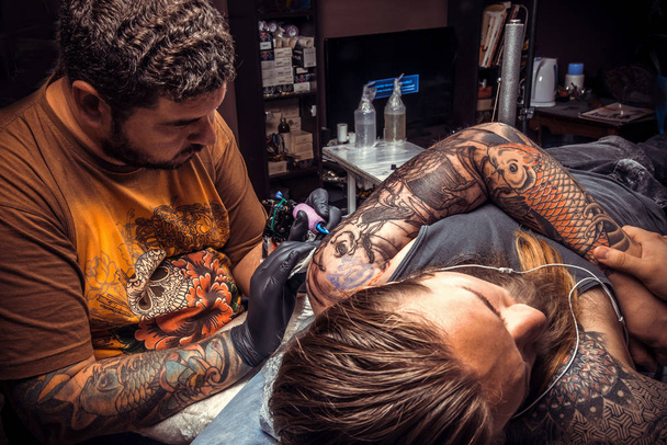 Профессиональный татуировщик делает татуировку в студии татуировки.
. - Фото, изображение