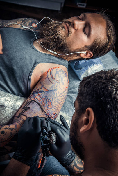 Tattooer mutatja a folyamat, hogy egy tetoválás, tetováló szalon. / szakmai tattooist tesz tattoo szalon. - Fotó, kép