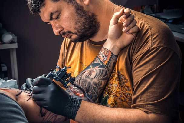 El maestro del tatuaje hace imágenes del tatuaje en el estudio del tatuaje. / Tatuaje profesional que hace un tatuaje en el salón del tatuaje
. - Foto, Imagen