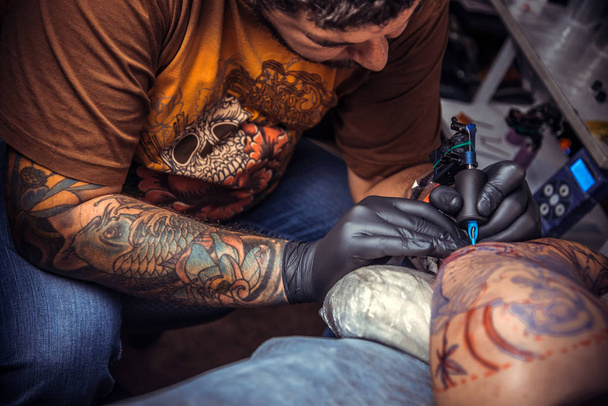 Tatoueur professionnel montrant le processus de fabrication d'un tatouage dans le salon de tatouage. / Tatoueur professionnel faisant le tatouage dans le salon de tatouage
. - Photo, image