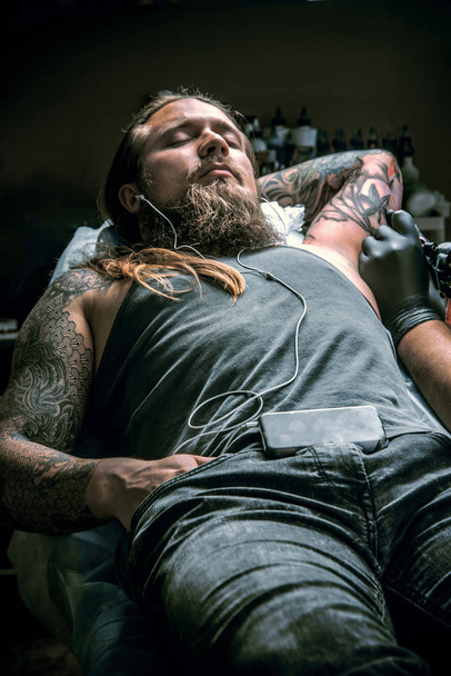Tattooer doing tattoo in tattoo studio - Foto, Imagen