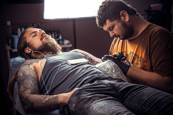 Maître de tatouage faisant un tatouage en studio de tatouage
 - Photo, image