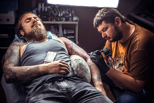 Master osoittaa prosessi tehdä tatuointi tatuointi studiossa. / Ammattimainen tatuoija tekee tatuointi kuvia tatuointi salonki
. - Valokuva, kuva