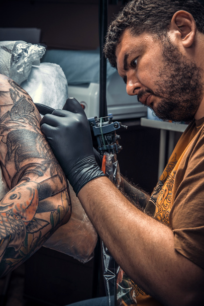 Profesional tatuador crear tatuaje en salón de tatuaje. / Maestro hace tatuaje fresco en salón
. - Foto, Imagen