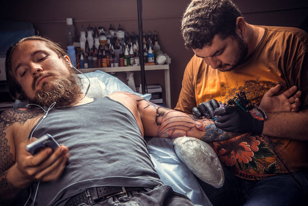 Tattooer working tattooing in studio./Master makes tattoo pictures in salon. - Фото, изображение
