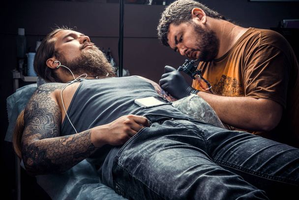 Tatoueur professionnel au travail en studio de tatouage. / Tatoueur professionnel travaille en studio
. - Photo, image
