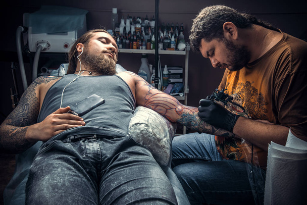 Especialista en tatuajes haciendo un tatuaje en el salón de tatuajes. / Tatuaje profesional hace que el tatuaje fresco en el salón de tatuajes
. - Foto, Imagen