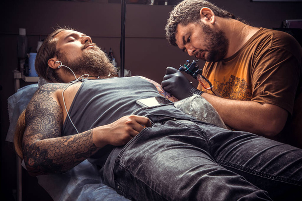 Tetováló mester a munkát, a tetoválás szalon. / szakmai tattooist mutatja a folyamat, hogy egy tetoválás, tetováló szalon. - Fotó, kép