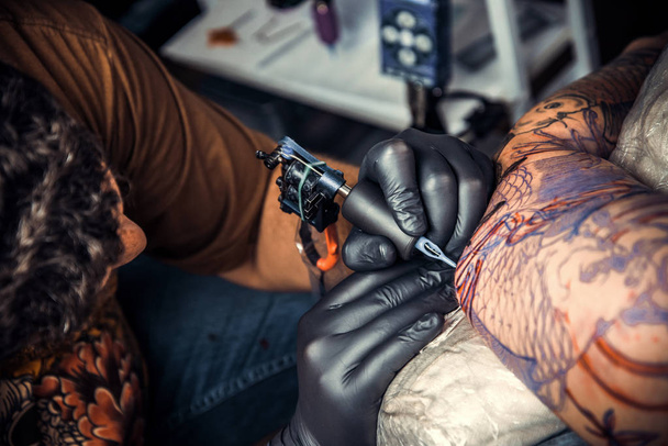 Tatoeëerder maken tattoo in tattoo salon. / professionele tatoeëerder maakt tattoo in tattoo salon. - Foto, afbeelding