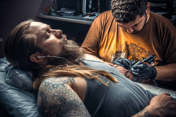 Il tatuatore professionista lavora in studio
 - Foto, immagini