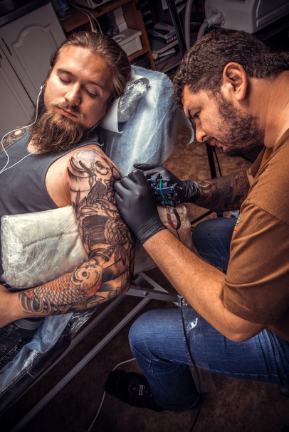 Maestro del tatuaje en el trabajo en el estudio del tatuaje
 - Foto, Imagen
