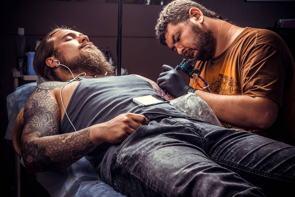 Tatuaje profesional haciendo un tatuaje en el salón de tatuajes. / Tatuaje profesional trabaja en el estudio de tatuajes
. - Foto, Imagen