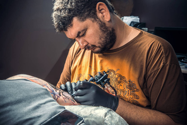 Tattoo master at work in tattoo parlor - Photo, Image