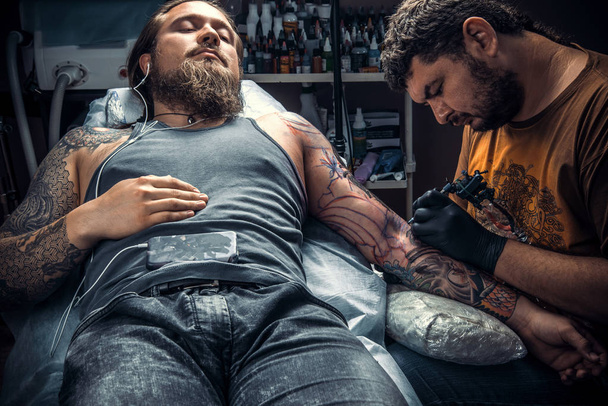 Especialista en tatuajes haciendo un tatuaje en salón de tatuajes
 - Foto, Imagen