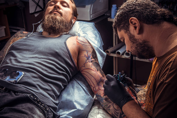 Maestro del tatuaje haciendo tatuaje en salón de tatuaje
 - Foto, imagen
