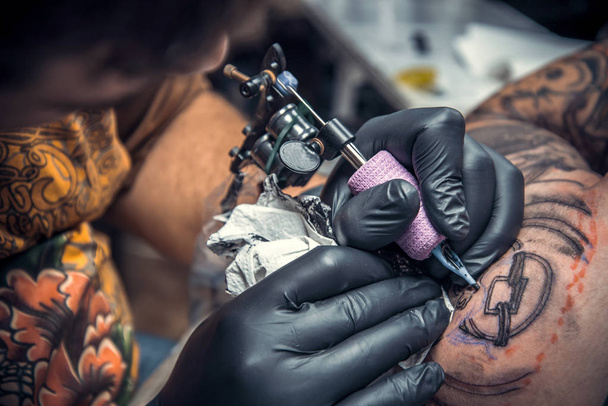 Татуировщик делает татуировку в тату-студии
 - Фото, изображение
