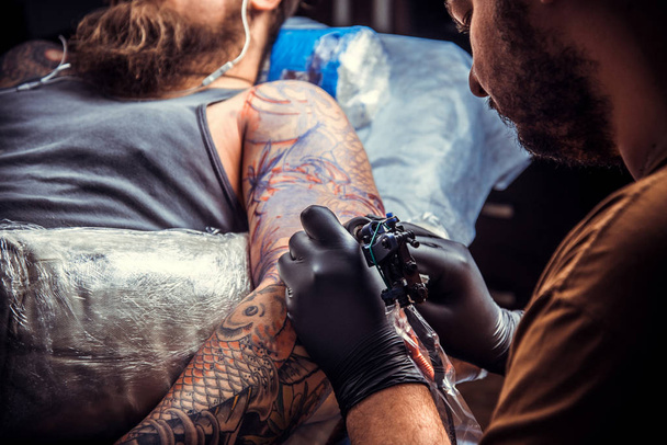 Maître de tatouage montrant le processus de fabrication d'un tatouage dans le salon de tatouage
 - Photo, image