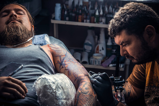 Maestro del tatuaje que muestra el proceso de hacer un tatuaje en el estudio del tatuaje
 - Foto, Imagen
