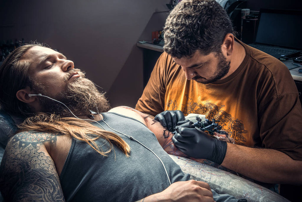 Professional tattooer makes cool tattoo in tattoo parlor - Photo, Image