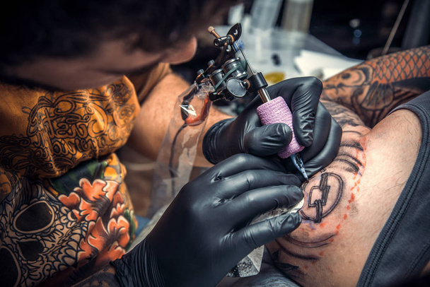 Фахівець з татуювання робить татуювання в татуювальному салоні
 - Фото, зображення