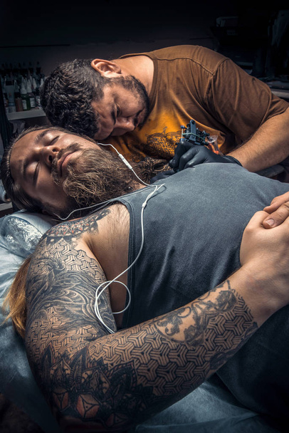 Tatoueur professionnel faisant un tatouage dans un salon de tatouage
 - Photo, image