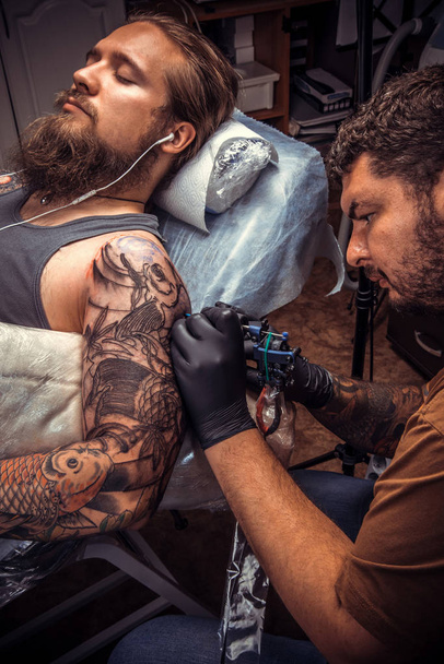 Tattooer werkt in tattoo salon - Foto, afbeelding