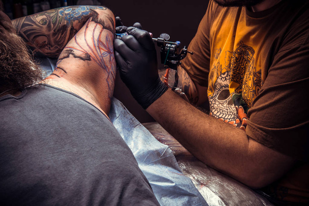 Maestro del tatuaje trabaja en estudio del tatuaje
 - Foto, imagen