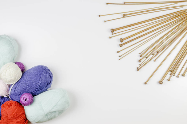 編み物の背景フレーム。木製の編み針と白地にカラフルな糸のペア - 写真・画像