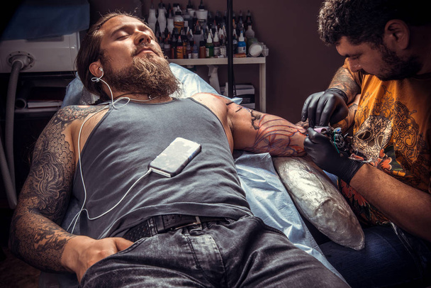 Professional tattooist works in tattoo studio./Professional tattooist making a tattoo in tattoo studio. - Photo, Image