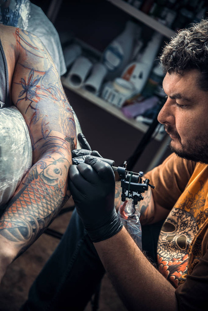 Professional tattooist makes tattoo in studio - Photo, Image